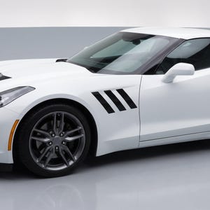 May include: A white sports car featuring a sleek body design with three distinct black diagonal vent stripes located on the front fender. The vehicle includes dark grey multi-spoke alloy wheels and a black side mirror housing.