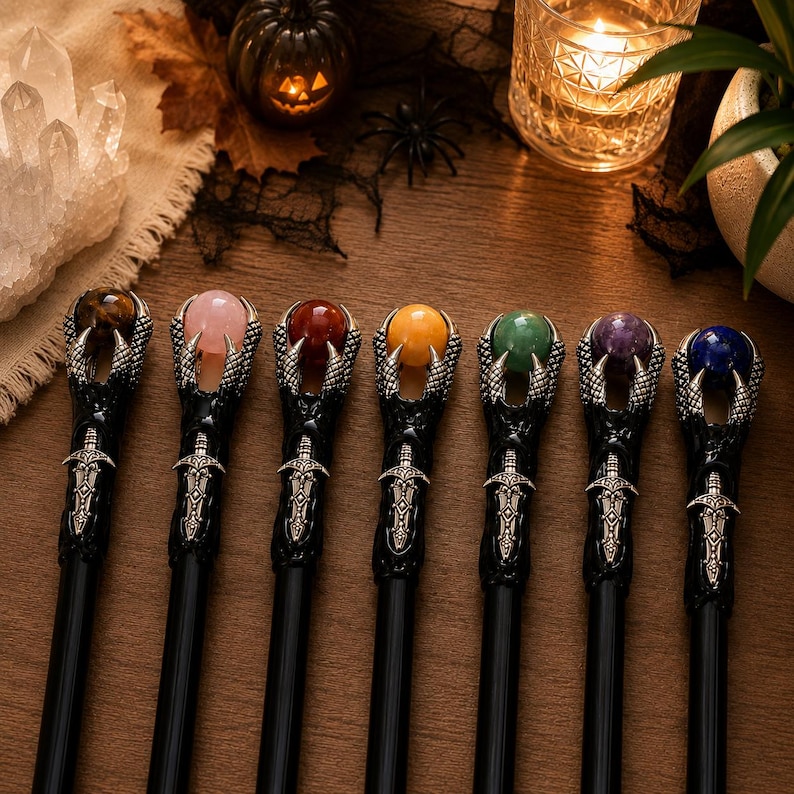 May include: Seven black wands arranged in a row, each featuring a silver-toned metal claw clutching a spherical gemstone. The gemstones are tiger's eye, rose quartz, carnelian, yellow jade, green aventurine, amethyst, and blue lapis lazuli.