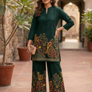 May include: A dark green tunic and wide-leg pants set featuring a vibrant bird and botanical print in yellow, red, and orange. The tunic has three-quarter sleeves, a mandarin collar with a button placket, and is paired with a small clutch.