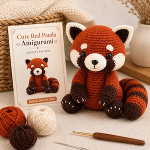May include: A crocheted red panda amigurumi toy with rust, cream, and dark brown yarn, accompanied by a printed pattern card titled Cute Red Panda Amigurumi, three balls of yarn in matching colours, a metal sewing needle, and a brown crochet hook.