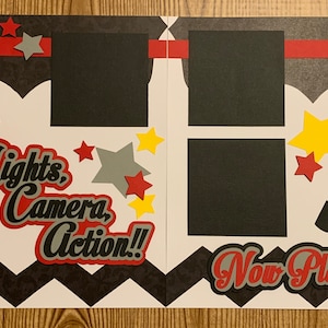 May include: A scrapbook page with a movie theme. It features a film reel, a dog, a movie clapperboard, and the phrases "Lights, Camera, Action!!" and "Now Playing.....". The color scheme includes red, black, gray, and yellow.