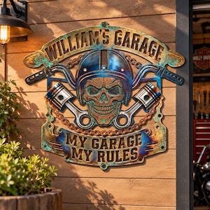 May include: A metal wall sign featuring a skull wearing a helmet, flanked by two engine pistons and motorcycle handlebars. The text reads WILLIAM'S GARAGE at the top and MY GARAGE MY RULES at the bottom. The sign has a blue and copper finish.