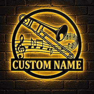 Könnte beinhalten: Ein kreisförmiges Wand-Schild aus schwarzem Metall mit einer hinterleuchteten Posaunen-Silhouette, Notenlinien und einem Violinschlüssel. Ein rechteckiges Banner am unteren Rand enthält den Text CUSTOM NAME in fetter Schrift.
