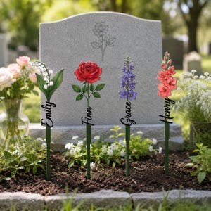 May include: Four decorative garden stakes featuring illustrated flowers: lily of the valley, a red rose, purple delphinium, and pink gladiolus. Each stake includes a black script name: Emily, Finn, Grace, and Henry, attached to a green stem.