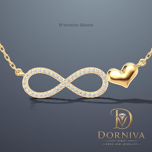 May include: A gold-colored necklace featuring an infinity symbol encrusted with small, clear gemstones and a solid gold heart pendant. The necklace is suspended from a delicate chain. The brand name "D'orniva Gems" is visible.