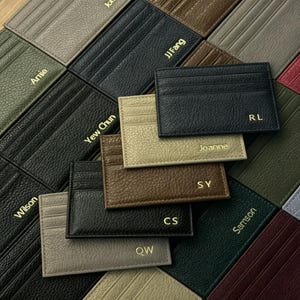 May include: A selection of personalised leather cardholders in colours such as black, brown, and beige. Each cardholder displays a gold-coloured name or initials. The cardholders have multiple card slots.