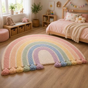Puede incluir: Una alfombra semicircular con un diseño de arcoíris formado por bandas concéntricas en rosa, naranja, amarillo, verde, azul y morado. La alfombra tiene una textura de pelo largo y está rematada con borlas de hilo a juego en el borde recto.