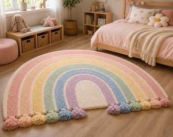 Pode incluir: Um tapete semicircular com um padrão de arco-íris composto por faixas concêntricas em rosa suave, laranja, amarelo, verde, azul e roxo. O tapete tem um pelo texturizado e felpudo, finalizado com borlas de fio a condizer na borda curva.