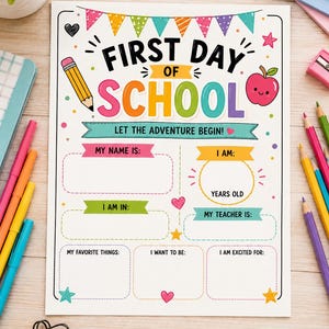 Op de afbeelding: Een wit papieren bord met kleurrijke tekst FIRST DAY OF SCHOOL LET THE ADVENTURE BEGIN. Het bevat een geel potlood, een rode appel en lege velden voor naam, leeftijd, klas, leraar, favoriete dingen, doelen en enthousiasme.