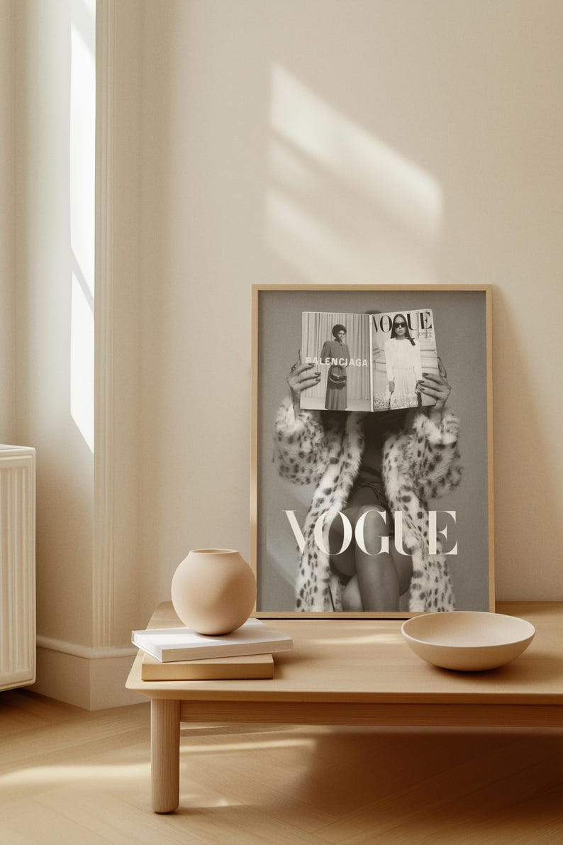 May include: A framed black and white wall art print featuring a person wearing a leopard print coat and holding a Vogue magazine in front of their face. The magazine cover displays the text Vogue and Balenciaga in a clear, bold typeface.