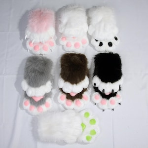 May include: Seven pairs of plush faux fur paw gloves in various colors including pink, white, gray, brown, and black. Each pair features soft fur, padded paw pads in pink or lime green, and small pointed claws attached to the fingertips.