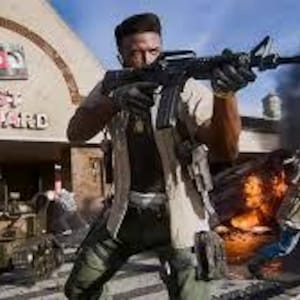 May include: A person holding a black rifle, with a military-style outfit, in front of a building with the text "FAST FORWARD". Other people are visible in the background, along with a tank and explosions.