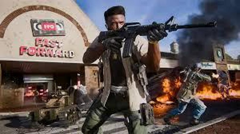 May include: A person holding a black rifle, with a military-style outfit, in front of a building with the text "FAST FORWARD". Other people are visible in the background, along with a tank and explosions.