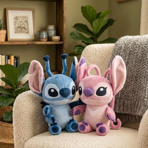 May include: Two plush toys featuring the characters Stitch and Angel. The blue Stitch plush has large ears and antennae, while the pink Angel plush has large ears and a heart-shaped chest patch. Both have large black eyes and soft fabric.