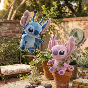 May include: Two plush toys featuring the characters Stitch and Angel. The blue Stitch plush is suspended in the air, while the pink Angel plush sits inside a terracotta pot. Both characters have large ears, antennae, and dark eyes.