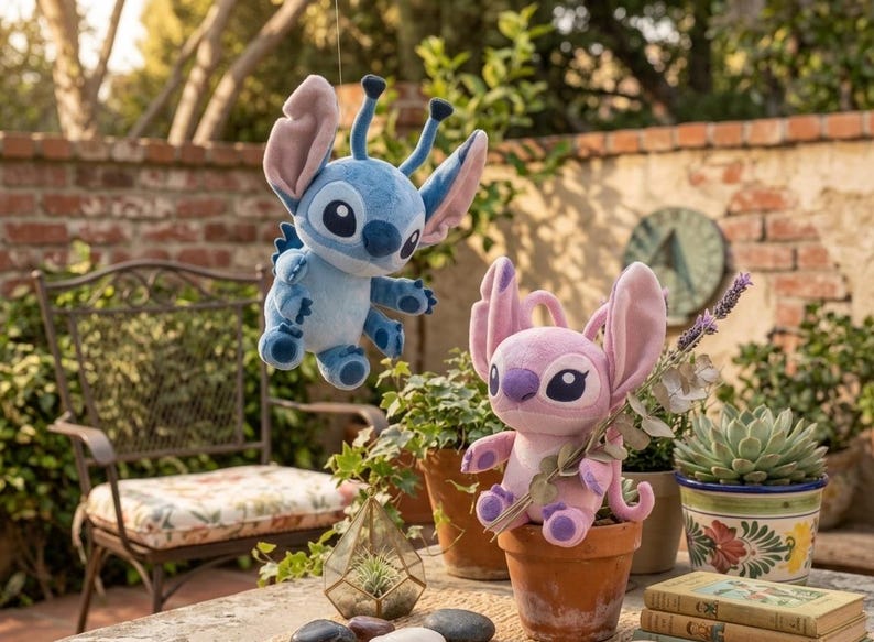 May include: Two plush toys featuring the characters Stitch and Angel. The blue Stitch plush is suspended in the air, while the pink Angel plush sits inside a terracotta pot. Both characters have large ears, antennae, and dark eyes.