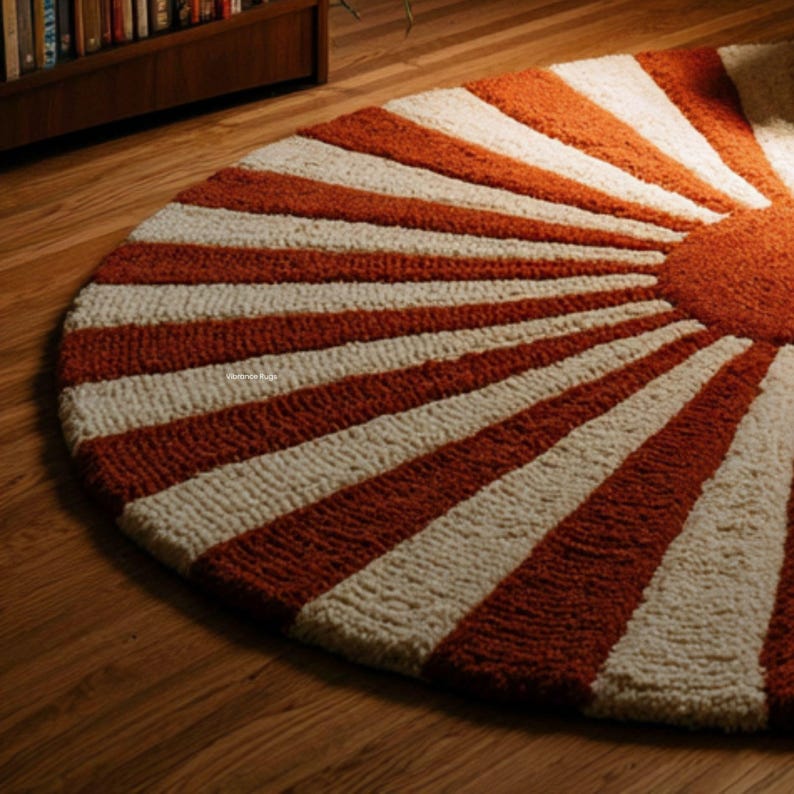 May include: A circular rug featuring a high-pile, tufted texture with a sunburst pattern. The design consists of alternating thick stripes in burnt orange and cream, radiating from a solid burnt orange circular center point to the outer edge.