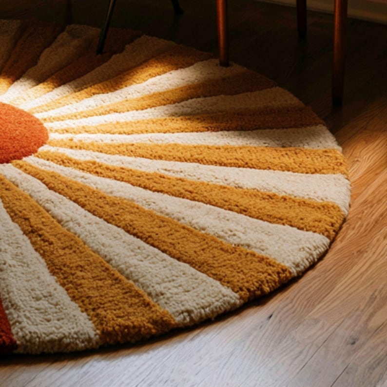 May include: A circular tufted rug featuring a sunburst pattern with alternating rays of mustard yellow and cream white. The center of the rug is a solid burnt orange circle, and the entire piece has a thick, textured pile construction.