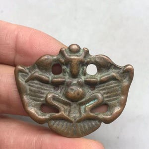Vintage-Anhänger aus durchbrochenem Kupfer mit Garuda-Motiv (Thogchag), tibetisches Amulett mit geflügeltem Vogel, das Gift abwehrt und spirituelle Schutzsymbole (Dharma) mit mehreren Löchern darstellt