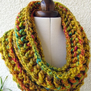 May include: A yellow, orange, and turquoise crocheted infinity scarf. The scarf is made with a chunky yarn and has a textured pattern.