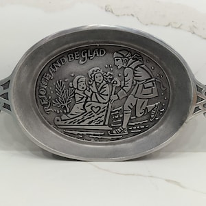 May include: An oval-shaped silver-toned metal tray with decorative handles on each side. The center features an embossed scene of a person pulling a sled with two figures, accompanied by the text "REJOICE AND BE GLAD" and a small heart icon.