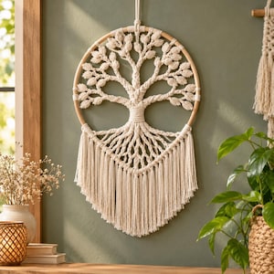 May include: A circular wall hanging featuring a macrame tree of life design crafted from off-white cotton cord. The tree is centered within a wooden hoop, with intricate braided branches and roots extending into a long, fringed bottom edge.