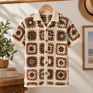 Peut inclure: Une chemise à manches courtes boutonnée, composée de carrés de crochet granny dans des tons crème, marron et vert olive. Le vêtement présente un col, une patte de boutonnage avant avec des boutons marron et un motif carré en maille ajourée.