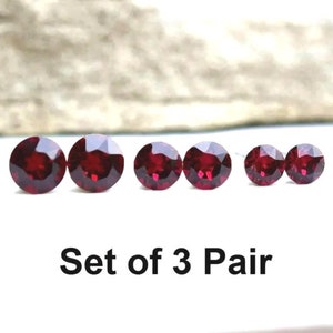 May include: Set of three pairs of red gemstone earrings. Each pair features a different size round gemstone.