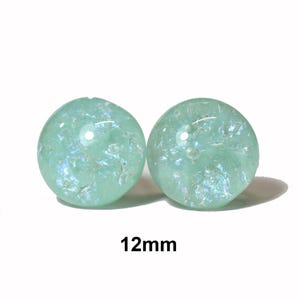May include: Two round, light green beads with iridescent flecks. Each bead is 12mm in diameter. The beads are set against a white background.