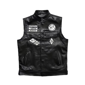 May include: A black leather waistcoat featuring a mandarin collar, two chest pockets, and two zipped waist pockets. The front is decorated with several white and black embroidered patches, including text reading MONGOLS, MFFM, NOMAD, and IN MEMORY OF.