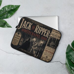 Op de afbeelding: Een zwarte laptophoes met een grafisch ontwerp in vintage-stijl met de tekst Jack the Ripper: Whitechapel 1888. De illustratie toont een donker, mistig straatbeeld van Londen met het silhouet van een persoon met een hoge hoed.
