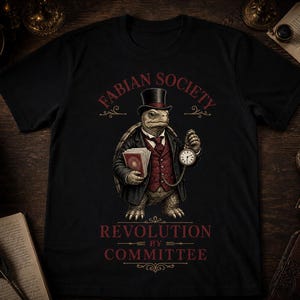 Op de afbeelding: Een zwart t-shirt met een afbeelding van een schildpad in een formeel pak, hoge hoed en gilet, die een stapel papieren en een zakhorloge vasthoudt. De tekst FABIAN SOCIETY staat erboven en REVOLUTION BY COMMITTEE eronder.