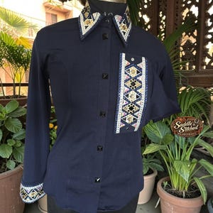 May include: A navy blue long-sleeve button-down shirt featuring a decorative panel on the left chest and matching accents on the collar and cuffs. The embellishments consist of geometric patterns with gold, black, and white crystals and studs.