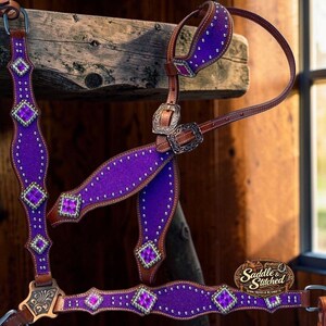 Peut inclure: Un licol pour cheval en cuir marron avec des incrustations à paillettes violettes, des clous en métal argenté et des cristaux violets carrés. L'ensemble comprend des boucles argentées ornées et un logo Saddle & Stitched Show Saddles & Blankets.