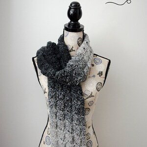 May include: A black and white ombre scarf is draped around a dress form. The scarf is crocheted and has a textured pattern. The text "the stitch'n mommy" is visible in the top right corner of the image.