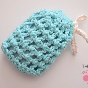 Op de afbeelding: Een lichtblauwe gehaakte zeepzak met een wit gehaakt trekkoord. De zak is gemaakt met een eenvoudig steekpatroon en heeft een los, luchtig gevoel.