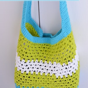 Könnte beinhalten: Eine gehäkelte Tragetasche in Grün, Weiß und Blau. Die Tasche hat eine breite, offene Oberseite und einen einzigen Trageriemen. Der Text "Summer Fun Market/Beach Tote" befindet sich oben im Bild.