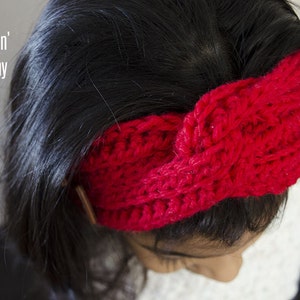 May include: A bright red crocheted headband with a knotted design. The headband is worn by a person with long dark hair.