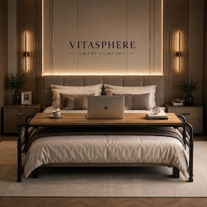 May include: A bedroom with a bed, a wooden table, and a laptop. The bed has a beige duvet and pillows. The table is made of wood and black metal. The text "VITASPHERE SMART COMFORT" is displayed on the wall.