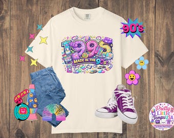 Könnte beinhalten: Ein cremefarbenes T-Shirt mit einer bunten Grafik und dem Text 1995 MADE IN THE 90s, umgeben von Illustrationen retroartiger Gegenstände wie einer Diskette, einem Kaugummiautomaten und einer Lavalampe, kombiniert mit einer blauen Jeans und violetten Turnschuhen.