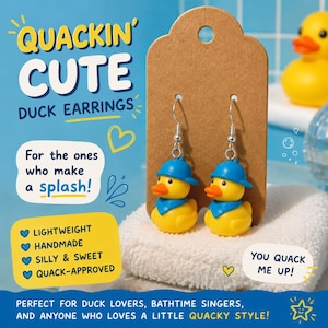 May include: Yellow duck earrings with blue hats and orange beaks are displayed on a brown card. The text "QUACKIN' CUTE DUCK EARRINGS" is at the top. The earrings are on a white towel with the text "YOU QUACK ME UP!"