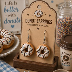 Könnte beinhalten: Donut-Ohrringe mit weißer Glasur, Schokoladenstreuseln und bunten Streuseln, präsentiert auf einer braunen Karte. Auf der Karte steht "DONUT EARRINGS - HANDMADE WITH LOVE". Ein Schild sagt "Life is better with donuts".