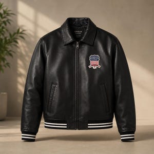 以下が含まれることがあります： フロントジッパー、ポインテッドカラー、長袖を備えた黒のレザージャケット。胸元には「American Classic」の文字が入った盾形のワッペンが付いています。袖口と裾は白と黒のストライプ柄のリブ編みになっています。
