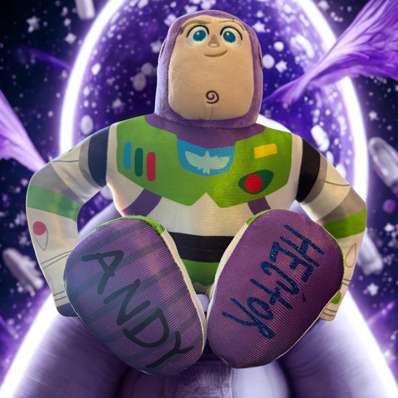 Puede incluir: Un mu&ntilde;eco de peluche de Buzz Lightyear, con un dise&ntilde;o de traje espacial morado y verde. Los nombres "ANDY" y "HECTOR" est&aacute;n impresos en las suelas de los pies. El fondo es una ilustraci&oacute;n con tem&aacute;tica espacial con acentos morados y blancos.