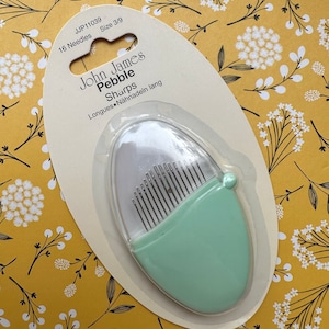 May include: A package of 16 John James Pebble Sharps needles, size 3/9, in a clear plastic case with a light green lid. The package is labeled "John James Pebble Sharps Longues = Nadeln lang".