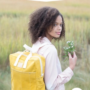 May include: A yellow backpack with white straps and a white zipper is featured in this image. The text "MAKING BACKPACK" is at the top, with "create your own backpack: regular & mini sizes" below it. The Noodlehead logo is at the bottom.