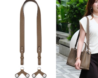 May include: A taupe leather bag strap with a pebbled texture and white contrast stitching, featuring two matching leather attachment pieces with silver-toned metal hardware, designed to be connected to a handbag for shoulder or crossbody carry.