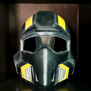 May include: A black and yellow helmet with a futuristic design. The helmet has a visor opening and yellow accents on the top and sides. The helmet is made of a hard material.
