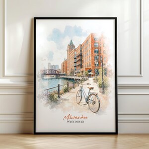 Könnte beinhalten: Ein gerahmter Aquarelldruck, der ein Stadtbild von Milwaukee, Wisconsin, zeigt, mit einem hellblauen Fahrrad auf einem Uferweg, roten Backsteingebäuden, einer Brücke im Hintergrund und dem Text Milwaukee WISCONSIN am unteren Rand.