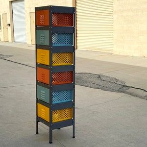 May include: A black metal storage unit with six colorful drawers. The drawers are painted in shades of yellow, orange, and blue. The unit has a simple design and is perfect for organizing small items.
